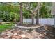 Landscaped backyard featuring mature trees surrounded by stone edging and a white vinyl fence for privacy at 1817 West Dr, Clearwater, FL 33755
