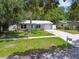Inviting single story home with lush lawn, concrete driveway, and surrounded by mature trees at 1817 West Dr, Clearwater, FL 33755