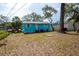 Turquoise home featuring a spacious backyard with trees, fresh exterior paint, and a patio at 1820 Douglas Ave, Clearwater, FL 33755