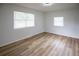 Bright bedroom featuring modern wood-look floors and ample natural light from two windows at 1820 Douglas Ave, Clearwater, FL 33755