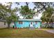 Turquoise home featuring a well-manicured lawn, white trim, and a welcoming front entrance at 1820 Douglas Ave, Clearwater, FL 33755