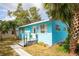 Charming turquoise home featuring a cozy front porch, well-maintained landscaping, and white shutters at 1820 Douglas Ave, Clearwater, FL 33755