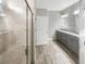 A spacious bathroom featuring a glass-enclosed shower, double vanity with stone countertops, and stylish gray cabinets at 19664 Ship Wheel Way, Land O Lakes, FL 34638