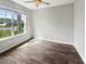 Bright bedroom featuring wood-look tile, ceiling fan, and a large window offering ample natural light at 19664 Ship Wheel Way, Land O Lakes, FL 34638