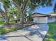 Charming single-story home with a well-maintained lawn, mature trees, and a concrete driveway leading to the garage at 2031 Dover Ct, Oldsmar, FL 34677