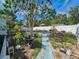 Lush backyard with a patio set, a wheelbarrow and bordered by a white fence at 2066 High Ridge Dr, Clearwater, FL 33763