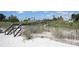 Picturesque beach access with dunes, wooden walkway, and glimpses of the ocean and nearby buildings at 3509 Oak Lake Dr, Palm Harbor, FL 34684
