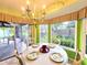 Eat-in kitchen features table set for four with views of an enclosed porch and backyard garden at 3509 Oak Lake Dr, Palm Harbor, FL 34684