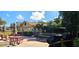 Outdoor restaurant patio with red picnic tables and umbrellas surrounded by greenery and palm trees at 3509 Oak Lake Dr, Palm Harbor, FL 34684