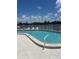 Inviting community pool with tiled deck, white fence, and beautiful water views at 376 Moorings Cove Dr # 6C, Tarpon Springs, FL 34689