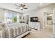 Spacious bedroom with light wood floors, a dresser with television, and an ensuite bathroom at 4177 Beeswax Ln, Land O Lakes, FL 34638