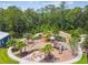 Aerial view of a playground with play structures, a fire pit, and seating surrounded by trees at 4177 Beeswax Ln, Land O Lakes, FL 34638