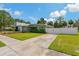 A tidy home and yard feature a white fence and driveway leading up to the home, freshly cut lawn at 433 Pineapple St, Tarpon Springs, FL 34689