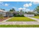Charming single-story home featuring a well-manicured lawn, modern gray paint, and a white fence at 433 Pineapple St, Tarpon Springs, FL 34689
