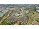 Scenic aerial view of a community with homes surrounding a large lake with lush greenery at 5411 Thistle Field Ct, Wesley Chapel, FL 33545
