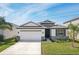 Charming single-story home featuring stone accents, a two-car garage, and well-maintained landscaping at 5411 Thistle Field Ct, Wesley Chapel, FL 33545