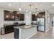 This is a modern kitchen featuring dark wood cabinets, granite countertops, and stainless steel appliances at 5411 Thistle Field Ct, Wesley Chapel, FL 33545