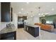 Spacious open-concept kitchen with dark cabinets, an island, and stainless steel appliances, flowing into the living room at 5411 Thistle Field Ct, Wesley Chapel, FL 33545
