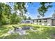Relaxing backyard features a stone fire pit, grassy lawn, and mature trees for shade at 6004 S 82Nd St, Tampa, FL 33619