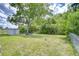 Large, grassy backyard features a fire pit, a shed, mature trees, and a chain-link fence at 6004 S 82Nd St, Tampa, FL 33619
