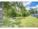 Large, grassy backyard features a fire pit, mature trees, and a chain-link fence at 6004 S 82Nd St, Tampa, FL 33619
