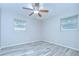 Bright bedroom features light wood flooring, a ceiling fan, and two windows with blinds at 6004 S 82Nd St, Tampa, FL 33619