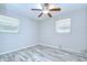 Bright bedroom features light wood flooring, a ceiling fan, and two windows with blinds at 6004 S 82Nd St, Tampa, FL 33619