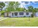 Charming single-story home featuring awnings, a carport, green grass, and beautiful landscaping at 6004 S 82Nd St, Tampa, FL 33619