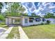 Inviting single-story home with awnings, a carport, landscaping, and a well-maintained lawn at 6004 S 82Nd St, Tampa, FL 33619