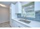 Stylish kitchen with a stainless steel sink, modern fixtures, white cabinets, and blue tile backsplash at 6004 S 82Nd St, Tampa, FL 33619