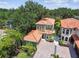 An aerial view of the house with a tile roof, brick driveway and lush landscaping creating a private oasis at 6008 Interbay Blvd, Tampa, FL 33611