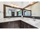 Bathroom vanity with double sinks, dark wood cabinets, granite countertops, framed mirrors and contemporary lighting at 6008 Interbay Blvd, Tampa, FL 33611