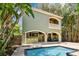 View of the back of the home with a pool, patio, grill, balcony and tropical landscaping at 6008 Interbay Blvd, Tampa, FL 33611