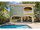 A view of the exterior back of the home showing a pool, patio, grill, and balcony at 6008 Interbay Blvd, Tampa, FL 33611