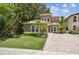 Charming two-story home boasts lush landscaping, a terracotta tile roof, and a brick driveway at 6008 Interbay Blvd, Tampa, FL 33611