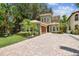 Charming two-story home boasts lush landscaping, a terracotta tile roof, and a brick driveway at 6008 Interbay Blvd, Tampa, FL 33611