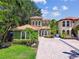 A beautiful home with a tile roof, arched windows, and a brick driveway surrounded by lush landscaping at 6008 Interbay Blvd, Tampa, FL 33611