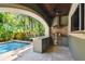 An outdoor kitchen with stainless steel appliances and a beautiful pool in a tropical setting at 6008 Interbay Blvd, Tampa, FL 33611