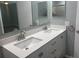 Bathroom featuring double vanity, white cabinets, and two mirrors at 6520 Thicket Trl, New Port Richey, FL 34653