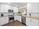 Modern kitchen featuring stainless steel appliances, white cabinetry, granite countertops, and wood-look flooring at 6826 Rosemary Dr, Tampa, FL 33625