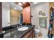 Well-lit bathroom featuring granite countertops, a decorative shower curtain, and neutral tiling at 704 Lyndhurst St # 624, Dunedin, FL 34698