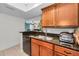 Kitchen with granite counters, black appliances, wood cabinets, stainless sink and dishwasher at 704 Lyndhurst St # 624, Dunedin, FL 34698