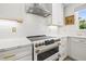Modern kitchen featuring white cabinets, subway tile backsplash, stainless steel range hood, and marble countertops at 743 43Rd Ne Ave, St Petersburg, FL 33703