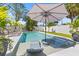 Backyard swimming pool with pristine water, a sunshade umbrella, and chaise lounges create an oasis for relaxation at 743 43Rd Ne Ave, St Petersburg, FL 33703