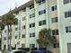 Multi-story light green condo building featuring palm trees and manicured landscaping at 801 83Rd N Ave # 107, St Petersburg, FL 33702