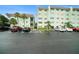 Exterior shot of condo buildings, a parking lot with multiple cars, and tropical landscaping at 801 83Rd N Ave # 107, St Petersburg, FL 33702