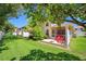 Spacious backyard patio with red chairs, lush lawn, and shaded area for outdoor relaxation at 8980 Antigua Dr, Seminole, FL 33777