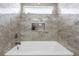 Modern bathtub with sleek faucet and shower head, surrounded by stylish grey tiling at 9047 Quail Creek Dr, Tampa, FL 33647