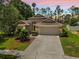 Charming single Gathering home with a lush lawn, mature trees and a two car garage at sunset at 9047 Quail Creek Dr, Tampa, FL 33647