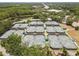 Wide aerial shot showing rows of tennis courts featuring shaded areas and lights, highlighting the community's active lifestyle at 9047 Quail Creek Dr, Tampa, FL 33647